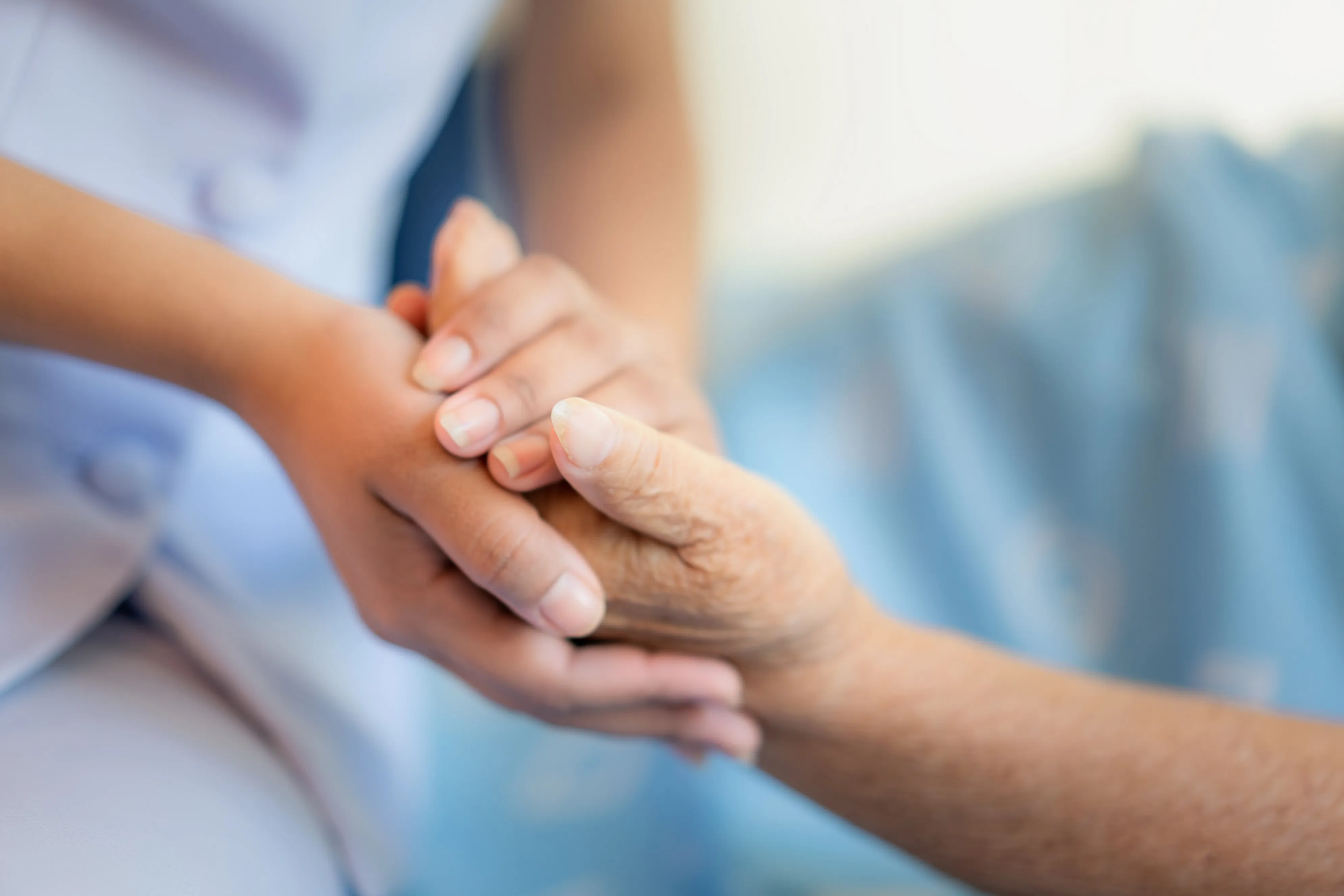 Eine Krankenschwester sitzt auf einem Krankenhausbett neben einer älteren Frau und hilft ihr. Konzept der Altenpflege